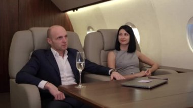 Bilgisayarın başında çalışan, şampanya içen, özel jet uçuran yeni bir projeyi tartışan genç bir çiftin yakın plan fotoğrafları.