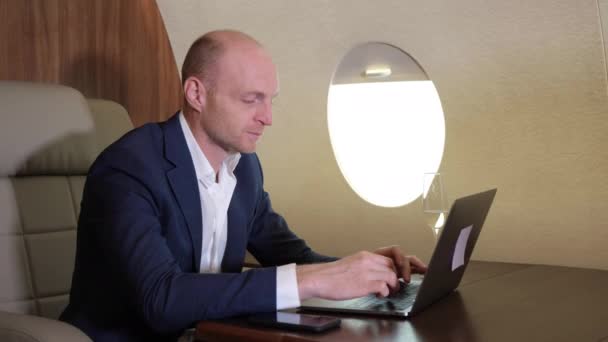 パソコンを使って仕事をしている若いビジネスマンの閉鎖自分の個人的な飛行機ビジネスジェットでビジネスをしている — ストック動画