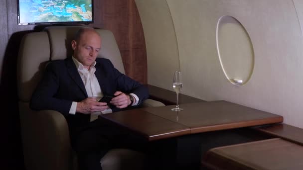 電話ビジネスを利用して働く若いビジネスマンのクローズアップ夜間飛行彼自身の個人的な飛行機ビジネスジェット — ストック動画