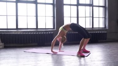 Spor kadın antrenman stüdyosunun orta planı. Genç bir bayan evde spor yapıyor. Kız sağa sola doğru eğiliyor, ısınıyor. Sağlıklı ve spor yaşam tarzı.