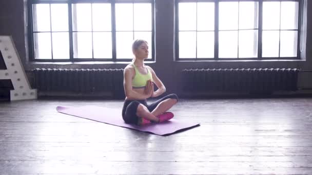 女性开始在家中坐在瑜伽垫上冥想 松懈的年轻无忧无虑的女子沉思着 瑜伽课上听着放松的女人 — 图库视频影像