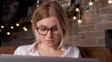 Gözlüklü, aşağıya bakan ve bilgisayar üzerinde çalışan ciddi bir kadının portresini yakından çek.