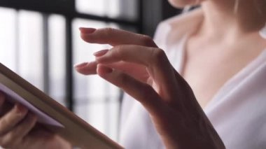 Elle Kapatma Bilgisayar Dokunma Ekranı ile. Gözlüklü genç bir iş kadını aşağı bakıyor ve büyük bir ofisin penceresinin yanında tablet üzerinde çalışıyor.