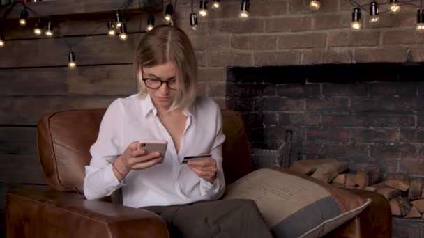 Evdeki Koltukta Oturan Elinde Kredi Kartı Akıllı Telefon Tutan Gülümseyen — Stok video