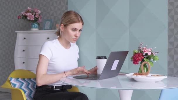 コンピュータで働く若いブロンドの女性コーヒーを飲み 明るい部屋のオフィスカフェで昼食休憩時間 — ストック動画