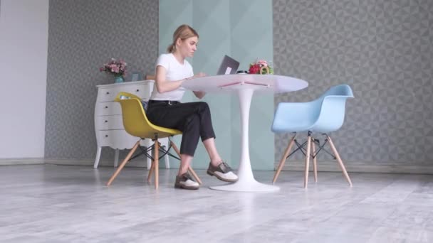 テーブルに座ってカフェで仕事をするためにノートパソコンを使う女性のフリーランスの肖像 — ストック動画