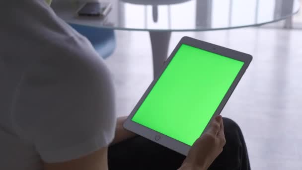 Femme assise sur le sol et utilisant une tablette verticale avec écran vert. Gros plan des mains de la femme avec un tampon. Seul, affichage.