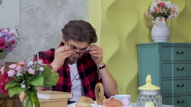 Jovem Senta Uma Cozinha Brilhante Coloca Óculos Toma Livro Café — Vídeo de Stock
