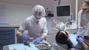 Diş hekimi ve asistan ameliyata hazırlanıyor, beyaz önlük ve maskeler, hastane bilgisayarı.