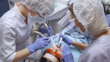 İki kadın dişçi dişlerini tıbbi aletlerle tedavi ediyor. Kadın dişçi ve bir hemşire klinikte dişlerini tedavi ediyor. Stomatoloji kavramı.