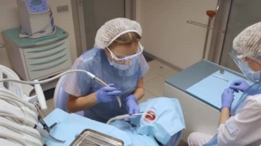 Mavi Eldivenli Dişçi Diş Hekimliği 'nde dişlerini koruyan kadınların dişlerini tedavi ediyor. Sağlık ve Tıp Konsepti.