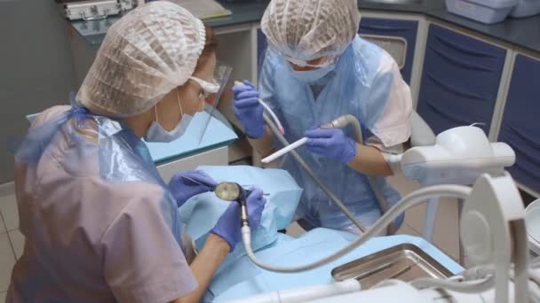Unga Kvinnor Två Tandläkare Blå Handskar Behandla Tänder Kvinna Bär — Stockvideo