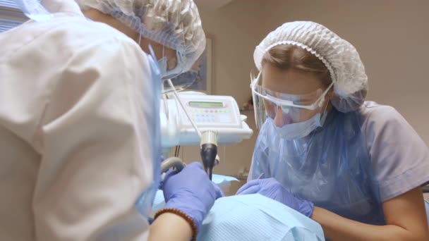 一名身穿蓝色手套的年轻妇女的特写两名牙医在牙科诊所治疗一名戴着护齿的妇女的牙齿 医疗及医疗的概念 — 图库视频影像