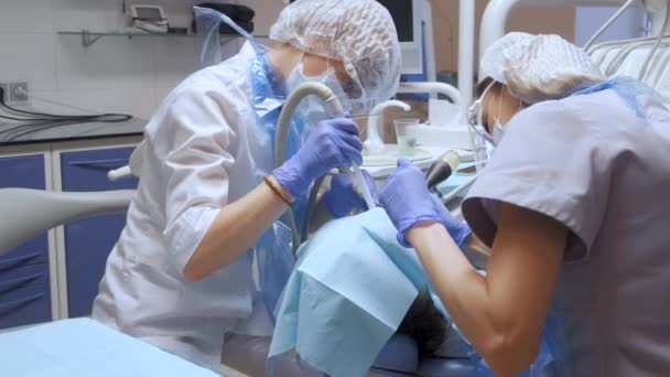 顔の保護で2人の若い女性歯科医師は 病院の歯科事務所で手術を行っています マスクと手袋を着用する 医療と医療の概念 — ストック動画