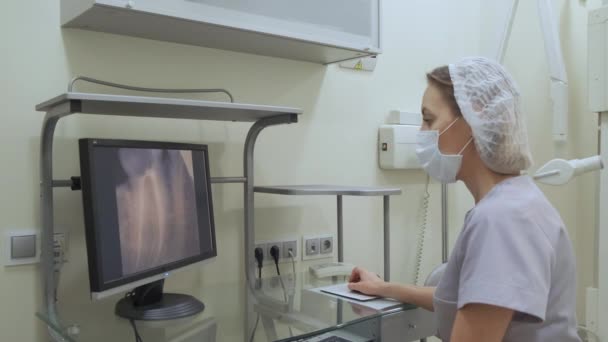 歯科用X線プレートを見る歯科医は 歯科用アーチを調べます コンピュータを使用している間のX線画像 — ストック動画