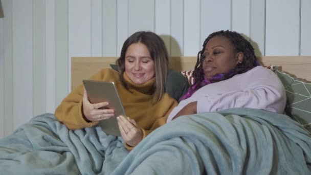 Afroamerikansk Och Europeisk Kvinna Som Ligger Sängen Med Hjälp Surfplatta — Stockvideo