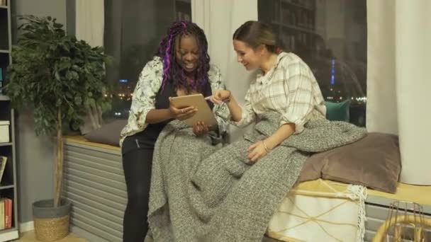寝室の女性の友人は デジタルタブレットを見て アフリカ系アメリカ人女性がタブレットを使用し ヨーロッパ人女性がスマートフォンを使用女性通信 楽しい 楽しさの概念 — ストック動画
