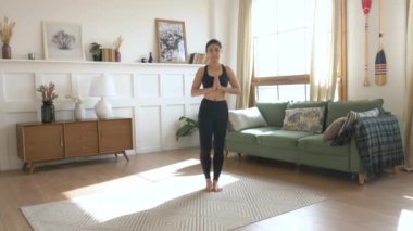 Genç Hintli kadın halıya çıkıp Namaste 'a bakıyor. Kameraya bakıyor. Yoga yapıyor, Siyah Spor Giyim Aydınlatma Odası yapıyor.