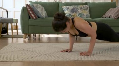 Genç bir Hintli kadın evde spor yapıyor, şınav çekiyor, Parlak bir yatak odası, siyah bluz ve tayt giyiyor. Spor Sağlıklı Yaşam Konsepti