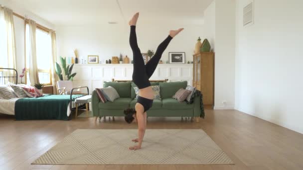 一个年轻的印度女芭蕾舞演员在家里训练 做手倒立练习 一间明亮舒适的房间 穿着黑色上衣和腿 运动理念健康生活 — 图库视频影像