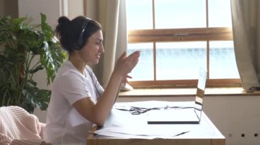 Gülümseyen Hintli Kadın, dizüstü bilgisayardan kablosuz kulaklık takıyor. Çevrimiçi web kamerası toplantısı, sanal eğitim, uzaktan çalışma iletişimi.