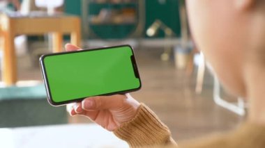 Yatay elleri kapat ve yeşil ekranlı akıllı telefonu tut. Krom anahtarlı yeşil ekran cep telefonu. Ürün yerleştirme için mükemmel.