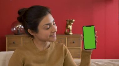 Gülümseyen Hintli Kadın elinde akıllı bir telefon tutuyor ve Gadget 'ı kullanarak yeşil ekran teknolojisini kullanarak yeni bir uygulama gösteriyor.