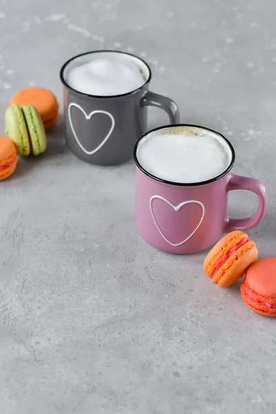 pink and gray cups with cappuccino. cups with  hearts, gray background. concept of romantic love, romantic breakfast, concept of romantic couple.  selective focus and copy space