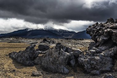 Central Highlands dramatik İzlanda lav manzara. Ön plan ve dağlar ve fırtınalı gökyüzü arka plan yıpranmış lav
