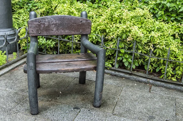 single seat wooden bench for people to sit on a plot with garden in Madrid. Spain