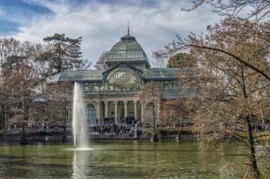 Madrid 'deki Retiro Parkı' nda bir sonbahar günü göletin önünde duran Kristal Saray 'ın görüntüsü. İspanya.