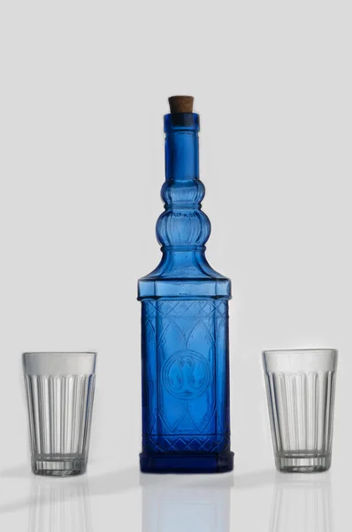 Blaue Glasflasche Mit Zwei Gläsern Isoliert Auf Weißem Hintergrund — Stockfoto
