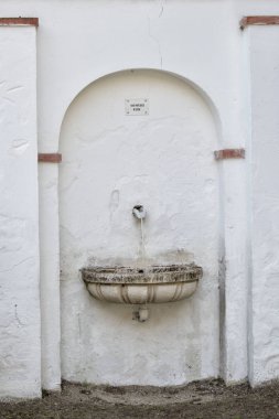 açık havada beyaz bir duvar üzerinde küçük taş çeşme