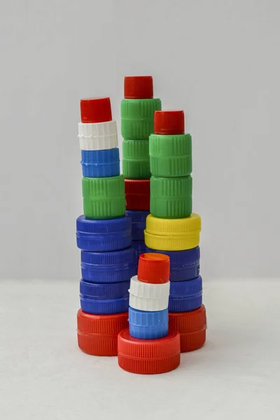 Tower of colorful plastic bottle caps isolated on white