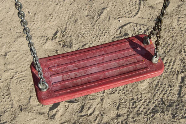 red swing isolated on sand background
