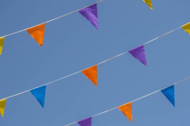 Arka planda mavi gökyüzü asılı renkli flamalar