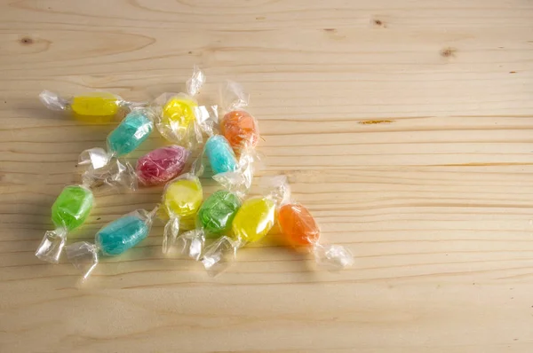 colored candies wrapped in transparent paper, isolated on wooden background