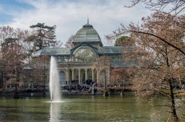 Madrid 'deki Retiro Parkı' nda bir sonbahar günü göletin önünde duran Kristal Saray 'ın görüntüsü. İspanya.