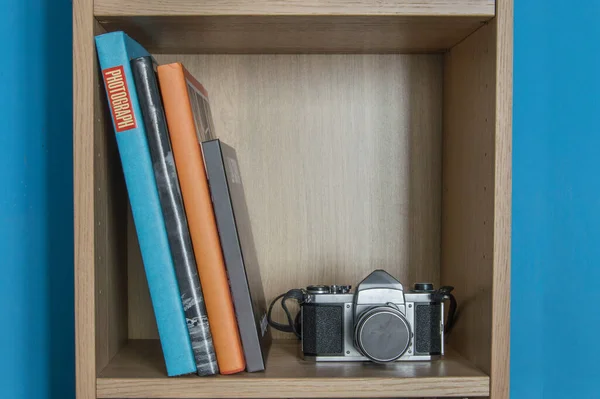 Houten Boekenplank Blauwe Achtergrond Met Drie Boeken Een Fotocamera — Stockfoto