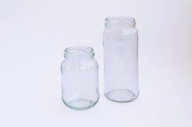 Beyaz arka planda izole edilmiş iki boş cam kavanoz.