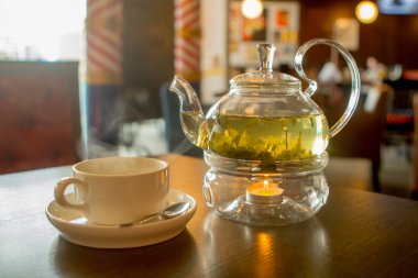 yeşil çay ve bir kafede ahşap bir masa üzerinde bir kupa ile şeffaf çaydanlık