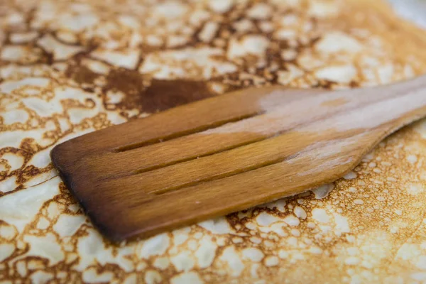 Close-up cooking pancakes in a frying pan with a wooden stick — Stock Photo, Image
