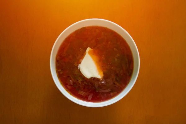 Remolacha roja de una remolacha con una rebanada de crema agria en un plato blanco sobre una mesa de madera —  Fotos de Stock