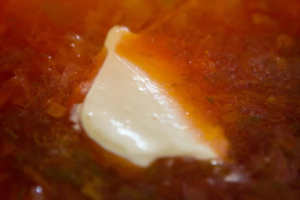 Remolacha roja de una remolacha con una rebanada de crema agria en un plato blanco sobre una mesa de madera — Foto de Stock
