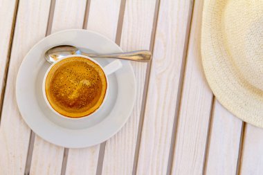 şapka ve beyaz kapuçino Kupası Beyaz ahşap bir masa üzerinde bir güneşli yaz gün üstten görünüm