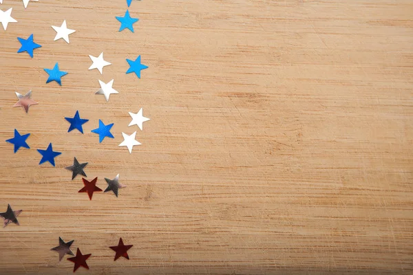 Konfeti yıldız ahşap arka plan üzerinde. Temmuz 4, bağımsızlık günü, kart, ABD bayrağı renklerde davet. Üstten görüntülemek, alan boş.