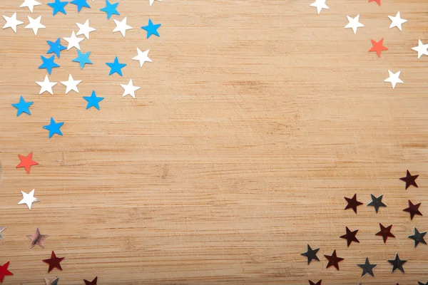 Confetti stars on wooden background. 4th July, Independence day, card, invitation in usa flag colors. View from Top , empty space.