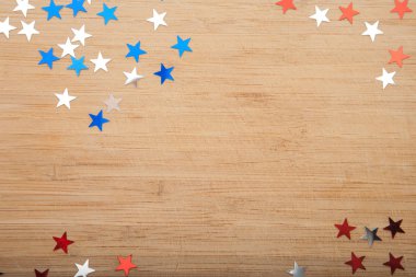 Konfeti yıldız ahşap arka plan üzerinde. Temmuz 4, bağımsızlık günü, kart, ABD bayrağı renklerde davet. Üstten görüntülemek, alan boş.