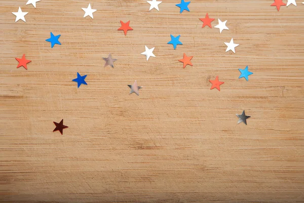 Konfeti yıldız ahşap arka plan üzerinde. Temmuz 4, bağımsızlık günü, kart, ABD bayrağı renklerde davet. Üstten görüntülemek, alan boş.