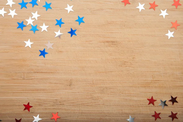 Confettis étoiles sur fond en bois. 4 juillet, fête de l'indépendance, carte, invitation aux couleurs du drapeau américain. Vue du haut, espace vide . — Photo